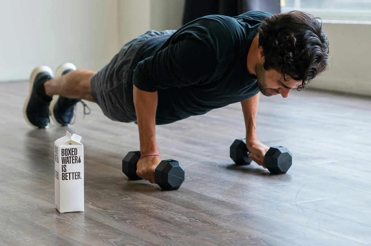 A person performing a weighted close-grip pushup to increase difficulty