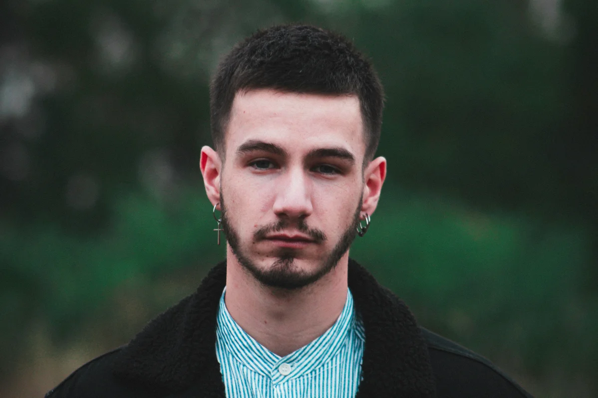 Close-up of a man with a patchy beard looking thoughtful