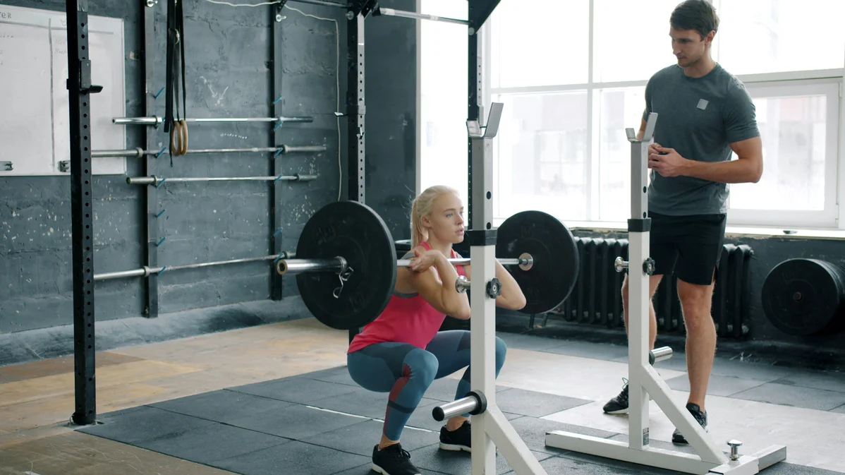 individual performing a barbell squat at the gym
